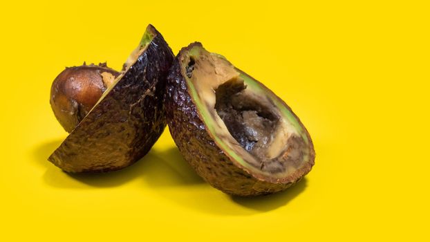 Bad avocado fruits Close up. Ugly fruits on Yellow background. Overripe avocado fruit cuts in halfs. Stop wasting food. Copy space.