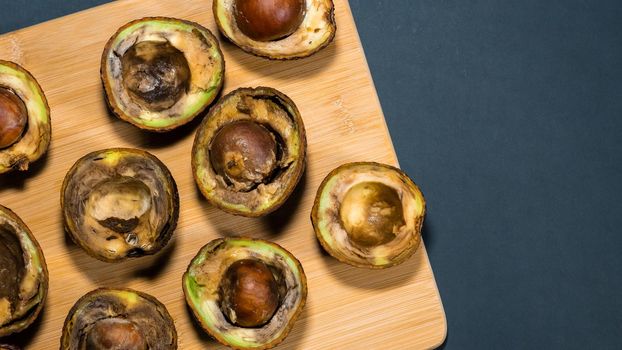 Overripe Avocado on wood Chipper dark background. Rotten Avocado Fruits in the kitchen on table. Unhelthy food concept. Stop wasting food. Copy space.