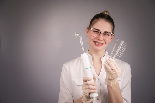 The cosmetologist doctor holds the darsonval device with different nozzles