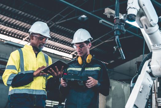 Factory workers working with adept robotic arm in a workshop . Industry robot programming software for automated manufacturing technology .