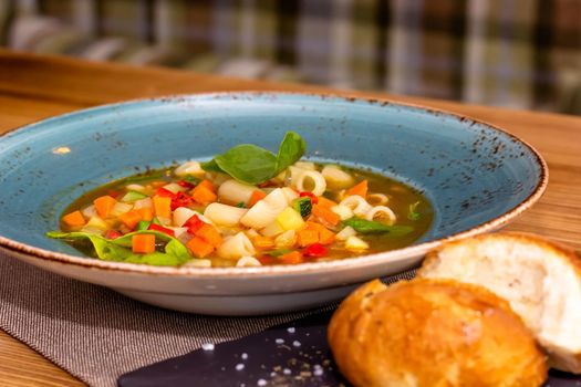 A bowl of minestrone soup with crackers on rustic vintage background.