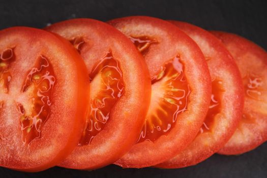 Close-up of tomato slices on a black background. View from above..
