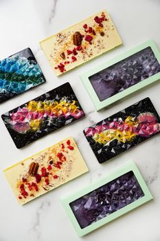 Hand-made bars of colorful chocolate on a light marble background. Homemade chocolate. Vertical photo