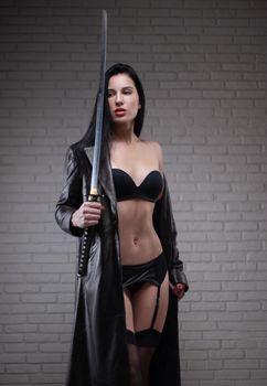 the sexy girl in a black leather raincoat with a katana in underwear and stockings
