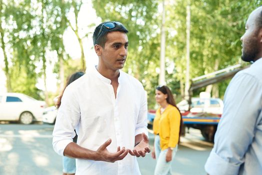 Happy two multiracial male best friends talking while standing in the street, african guy talking to afghan buddy at outdoor meeting. Smiling multiethnic young people, multicultural friendship reunion concept.
