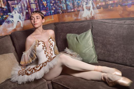 beautiful ballerina in a wearing a white tutu sits on the Sofa