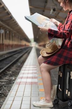 Pretty Young traveler woman looking on maps planning trip at train station. Summer and travel lifestyle concept