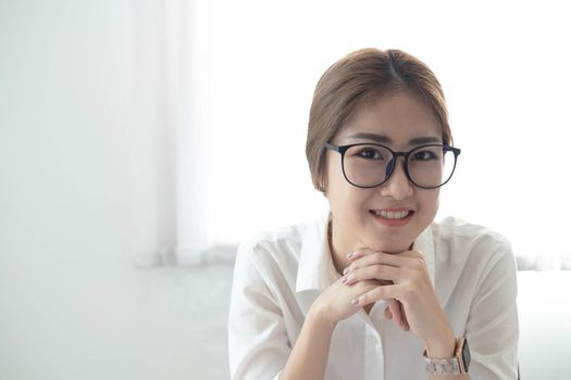 Beautiful smiling Asian businesswoman wearing glasses at office. Looking at camera..