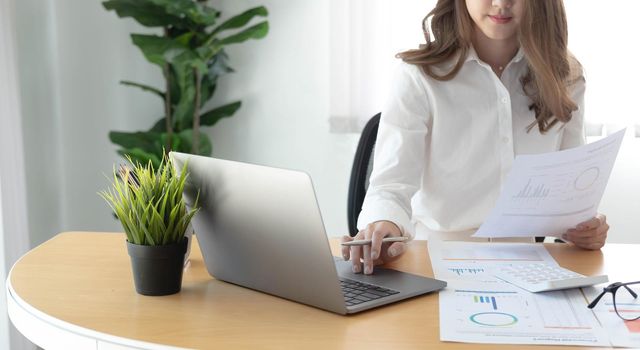 Young Asian businesswoman is happy to work at the modern office using a laptop computer..