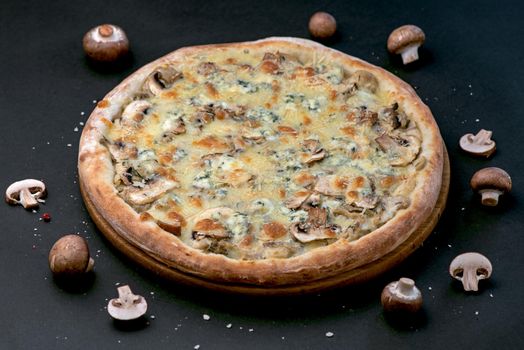 Homemade Pizza with mushrooms and cheese. On a black stone background.