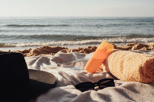 Sunscreen Lotion, Towel, Bottle of Water and Sunglasses with Hat Lying on Plaid by Sea, Vacation Concept