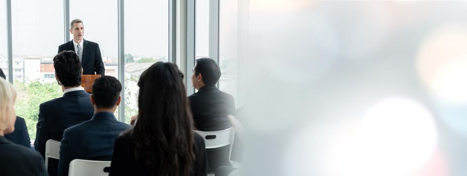 Group of business people meeting in a seminar conference widen view . Audience listening to instructor in employee education training session . Office worker community summit forum with speaker .