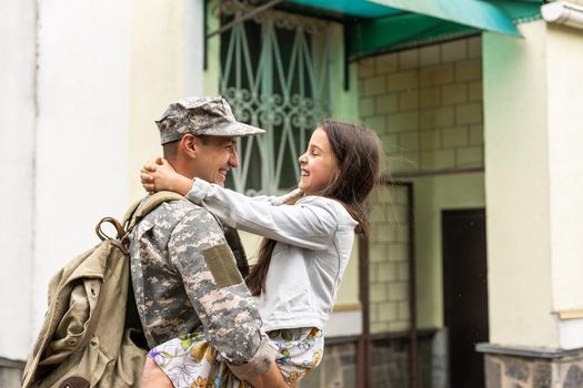 Soldier in camouflage meeting his daughter outdoors.