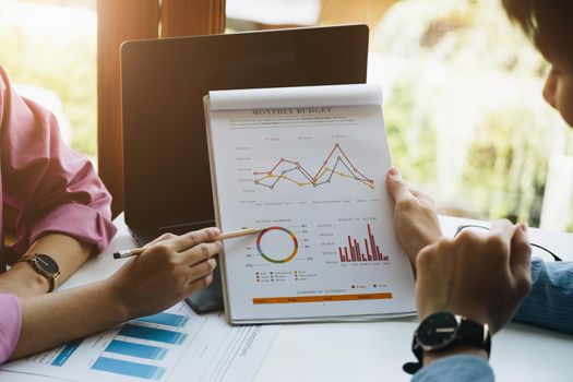 Negotiation, Analysis, Discussion, Asian woman economist and marketer pointing to a financial data sheet to plan investments to prevent risks and losses for the company.