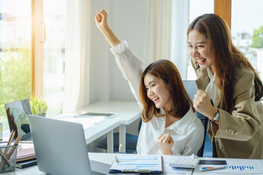 startup, successful, portrait of two young Asian women working on laptop computers, delighted with sales targets planned marketing.