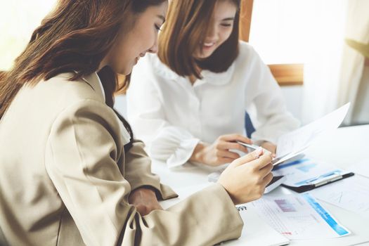 Negotiation, Analysis, Discussion, Asian woman economist and marketer pointing to a financial data sheet to plan investments to prevent risks and losses for the company.