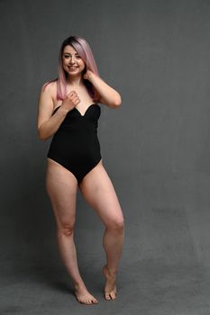 Caucasian woman in full growth in a swimsuit with a smile looks to the side