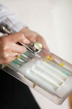 Close-up of the hands of a female pastry chef who sprays food paint with a pastry airbrush in the kitchen when making chocolates.