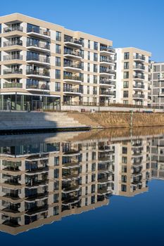 Modern apartment buildings with a perfect reflection in a small canal seen in Berlin, Germany