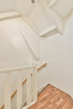 White spiral stairway connecting levels of contemporary house with wooden floor and white walls