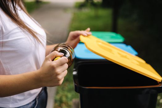 Closeup portrait woman hand throwing empty plastic water bottle in recycling bin.