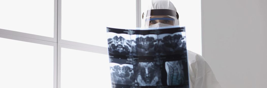 Close-up of qualified doctor observing radiograph of back, examine x ray in protective uniform. Film of patients analysis to find best solution for operation. Medicine, healthcare concept