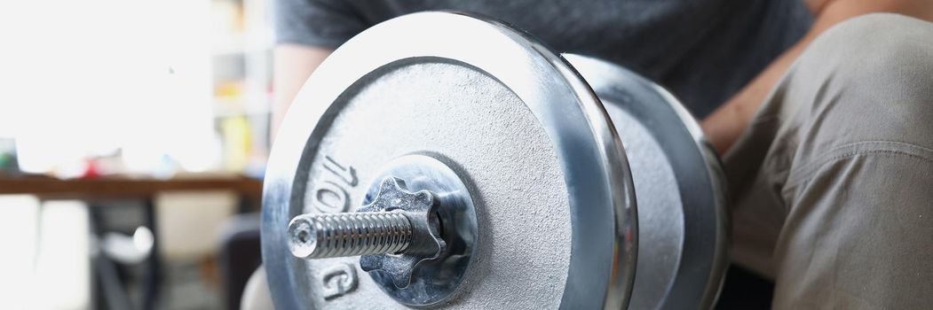 Close-up of man lifting heavy metal dumbbell with one hand. Train body for muscles, healthy living, gym at home. Sport, active lifestyle, physical activity, workout concept