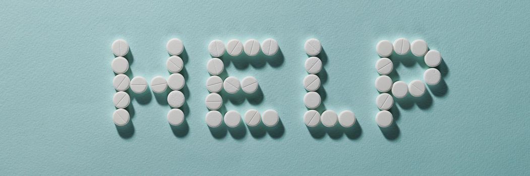 Top view of help lettering made with pills, drug prescription for treatment, pharmaceutical medicament, oral tablets. Medicine help, healthcare, illness, support organism concept