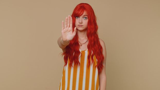 No stop. Serious woman say no, hold palm folded crossed hands in stop danger gesture, warning of finish, prohibited access, declining communication, body language. Redhead one girl on beige background