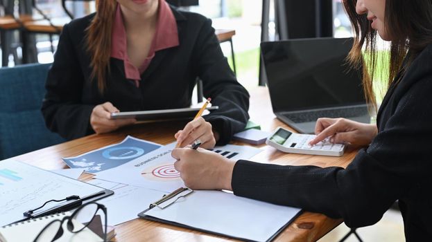 Cropped shot two professional businesswoman analyzing financial document together at office.