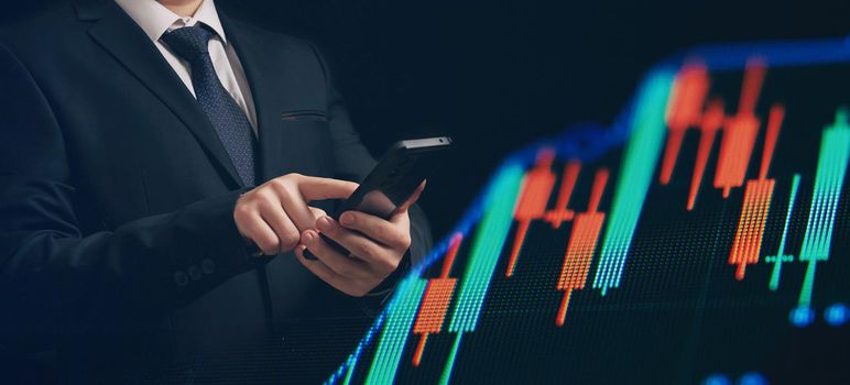 Man using smartphone with graphs analysis candle line and foreign currency rate on bokeh colors light. Manager analyzing investment statistics and indicators on dashboard for trading products.