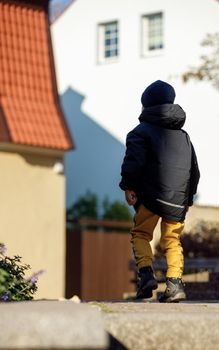 A silhouette of a little boy wearing a jacket in the old town during the fall.