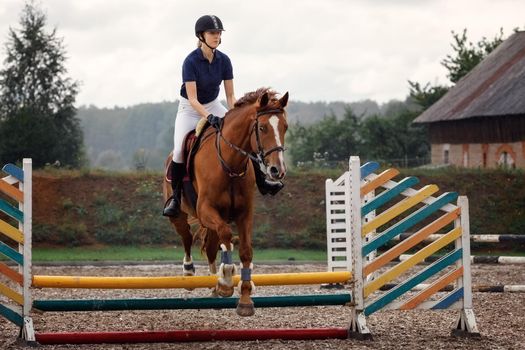 Equestrian jumper - Young girl jumping with cherry horse she completing a jump.