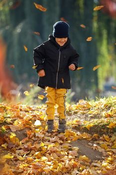 Happy child playing in yellow autumn leaves. Simple happiness. Sweet childhood memories.