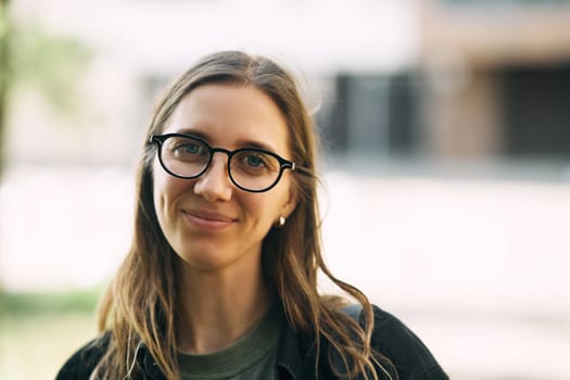 Portrait of a smiling young girl with glasses in the park. High-quality photo