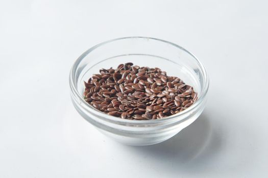 close up of flax seeds on in a glass bowl on white ,