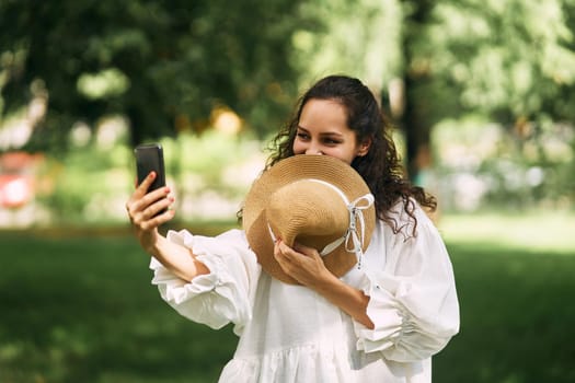 Young beautiful girl in a hat makes a selfie on her phone in the park. High quality photo