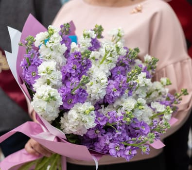 Woman holding bouquet of white and lilac matthiols