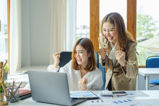 startup, successful, portrait of two young Asian women working on laptop computers, delighted with sales targets planned marketing.