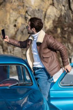 a man takes a selfie on the phone while standing near the car