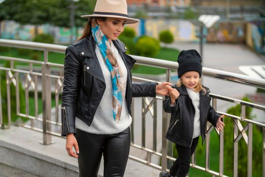 stylish mom and daughter walk the city