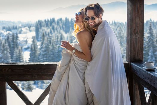 couple in winter in blankets on the background of mountains