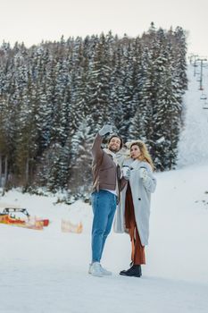 young couple taking a selfie on the background of a snowy mountain