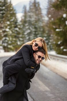 the girl climbed on the guy's back and walk along the road cheerfully