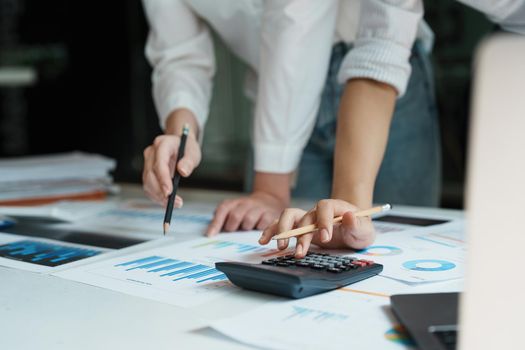 financial, Planning, Marketing and Accounting, Asian woman Economist using calculator to calculate investment documents with partners on profit taking to compete with other companies.