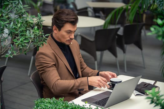 businessman sitting at a table in a cafe with a laptop