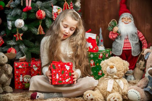 Girl with a gift box in her hands on the background of a christmas tree
