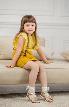 a girl in a yellow suit sits on sofas