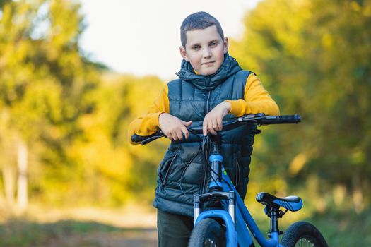 portrait of a boy with a bicycle against the background of an autumn forest