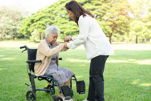 Caregiver help and care Asian senior or elderly old lady woman patient sitting and happy on wheelchair in park, healthy strong medical concept.